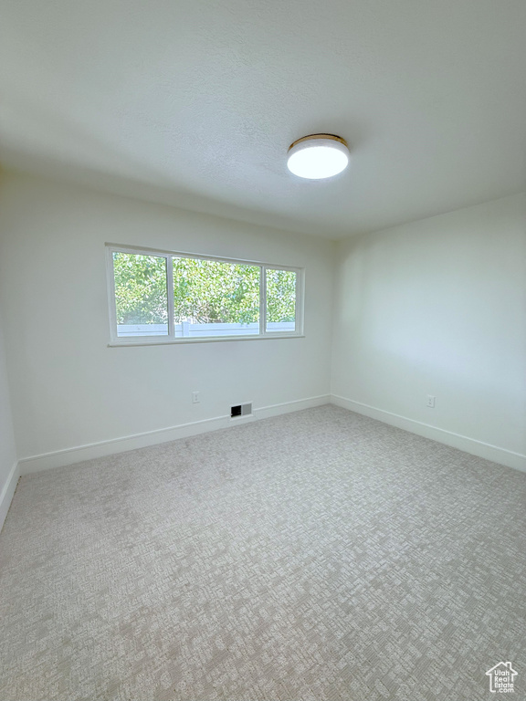 Empty room featuring baseboards and carpet flooring