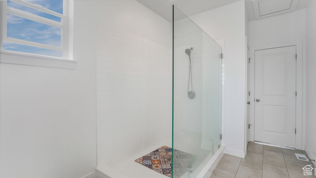 Full bathroom with a tile shower, tile patterned floors, and baseboards