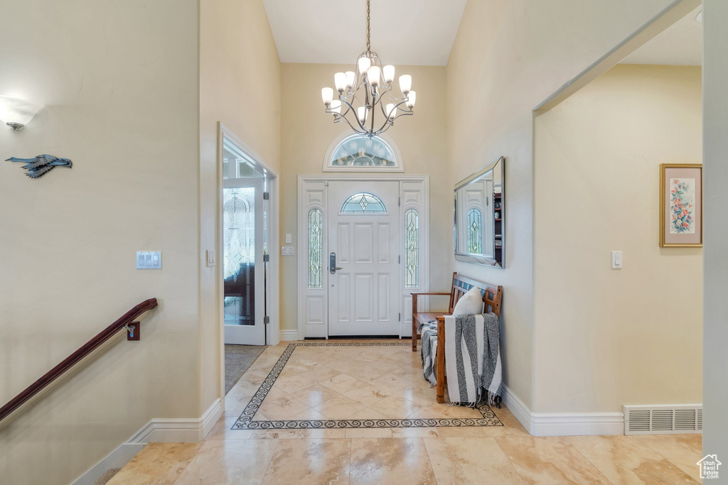 Foyer entrance featuring a chandelier, healthy amount of natural light, baseboards, and a high ceiling