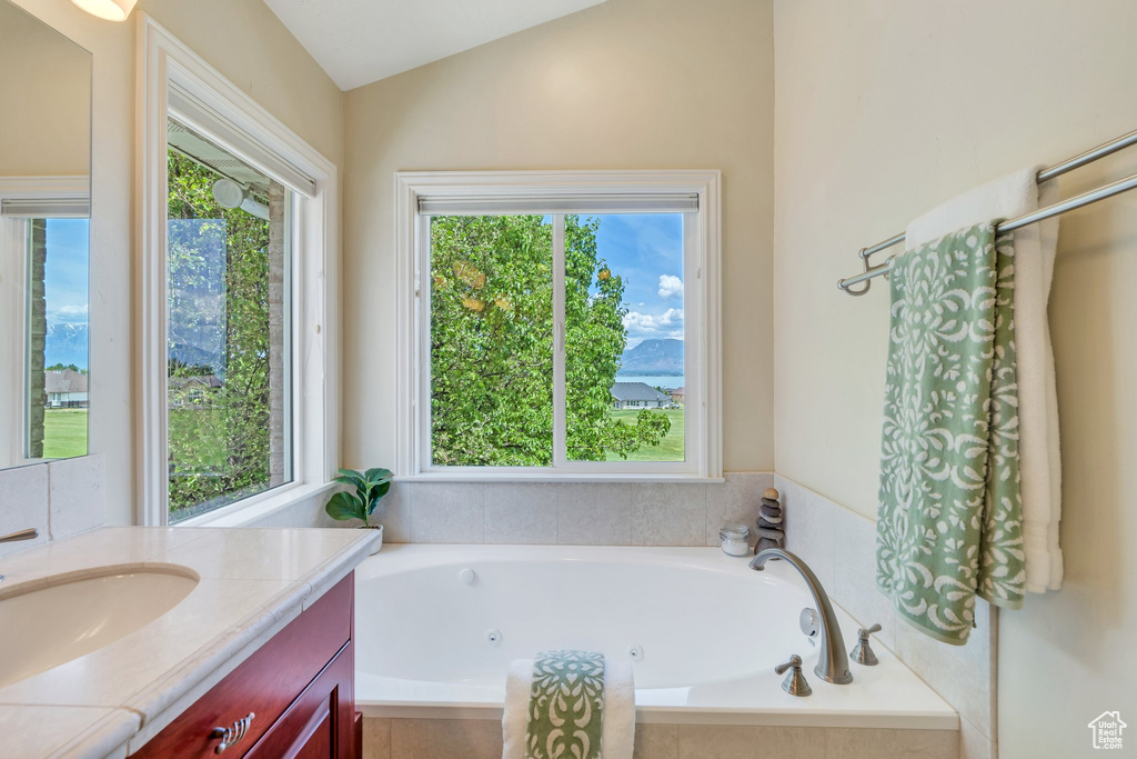 Full bath with vanity, a whirlpool tub, and lofted ceiling