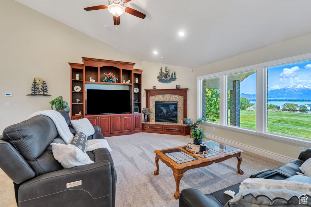 Living area with ceiling fan, light carpet, recessed lighting, vaulted ceiling, and a glass covered fireplace