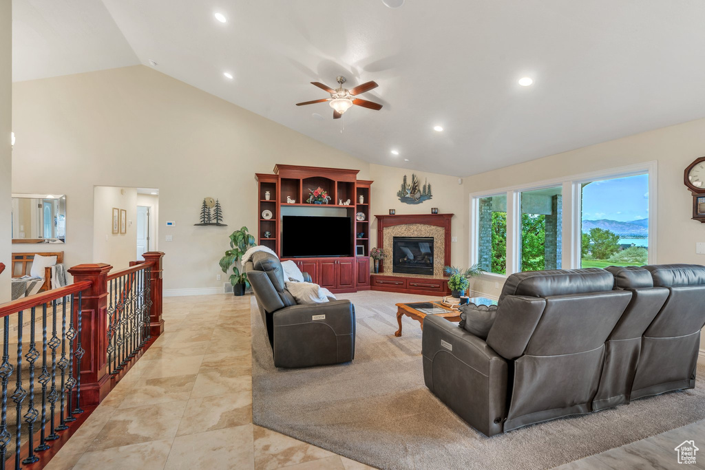 Living room featuring a ceiling fan, recessed lighting, high vaulted ceiling, a glass covered fireplace, and light marble finish floors