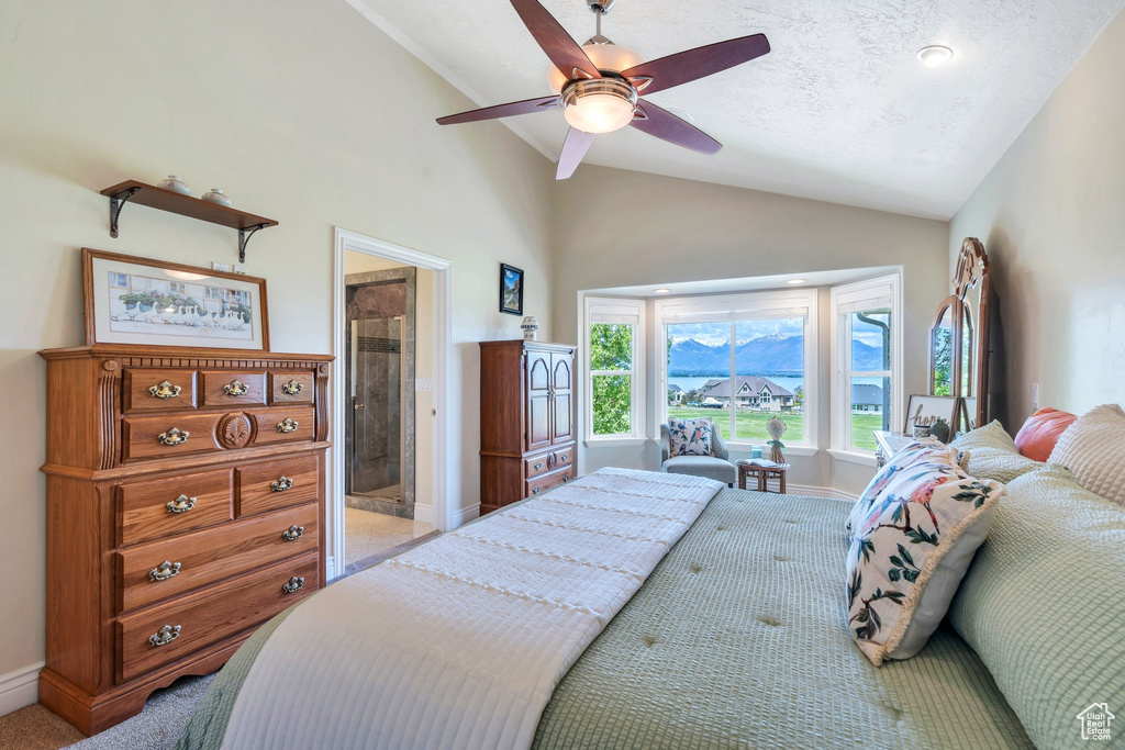Bedroom with vaulted ceiling, light carpet, baseboards, ceiling fan, and ensuite bath
