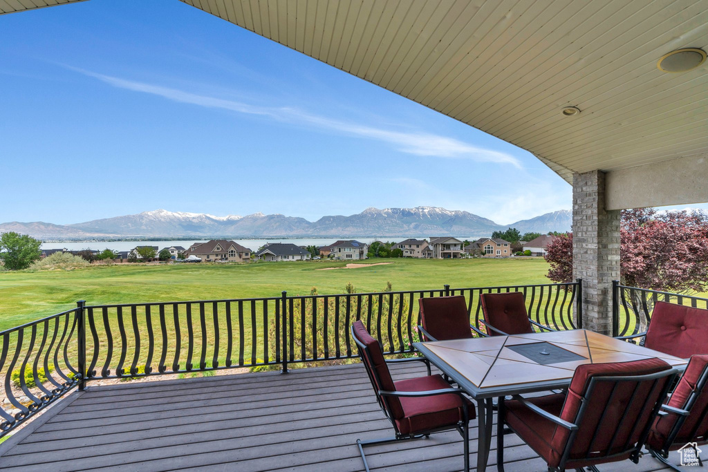 Wooden terrace featuring a mountain view, outdoor dining area, and a yard