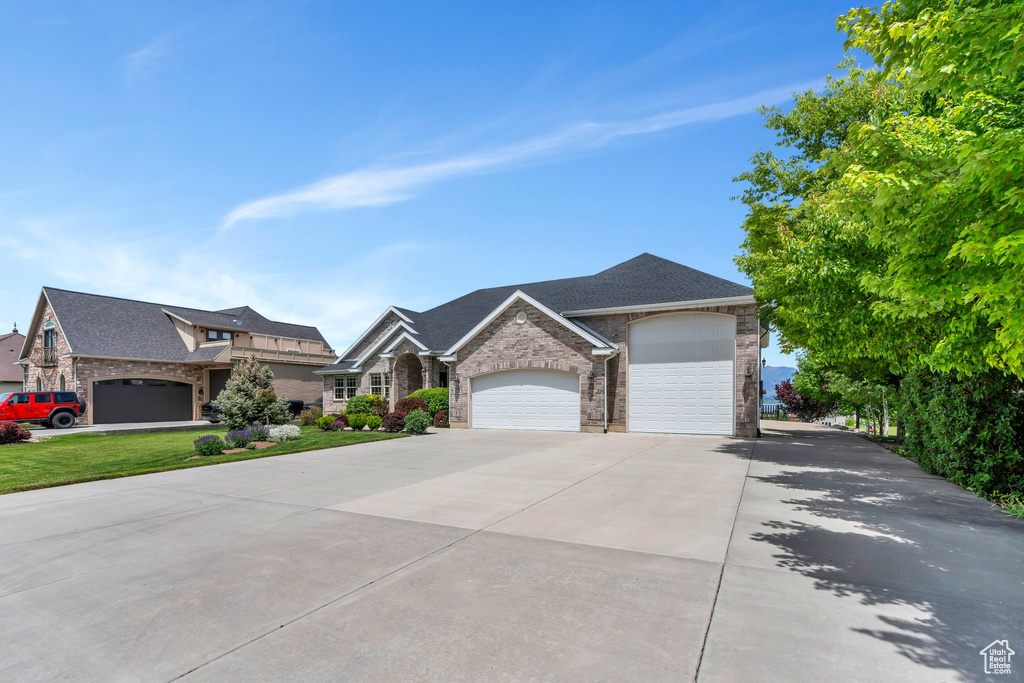 View of front of property featuring stone siding, concrete driveway, and a garage