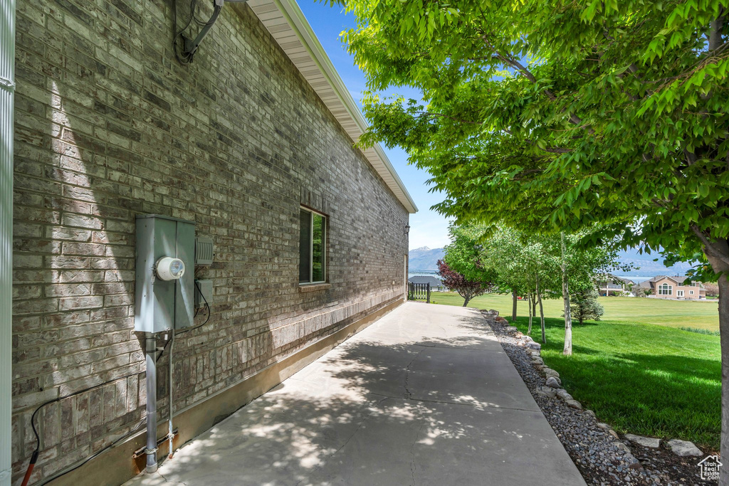 View of side of home featuring a yard, a patio area, and brick siding
