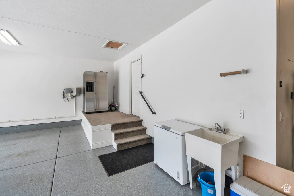Garage featuring stainless steel fridge with ice dispenser and white refrigerator