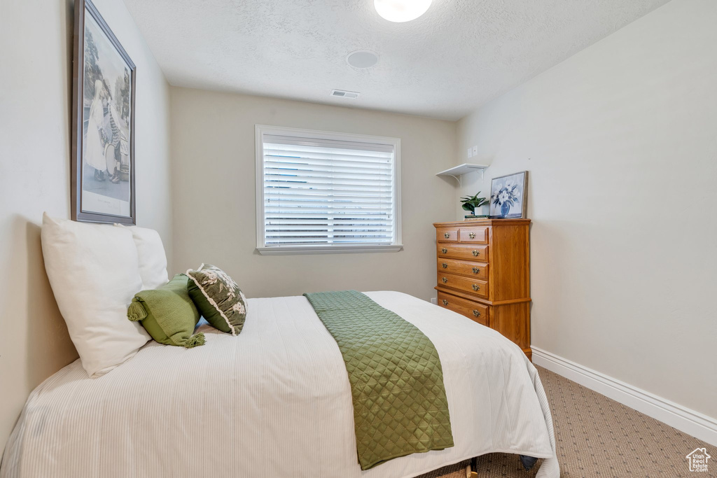 Carpeted bedroom with baseboards and a textured ceiling