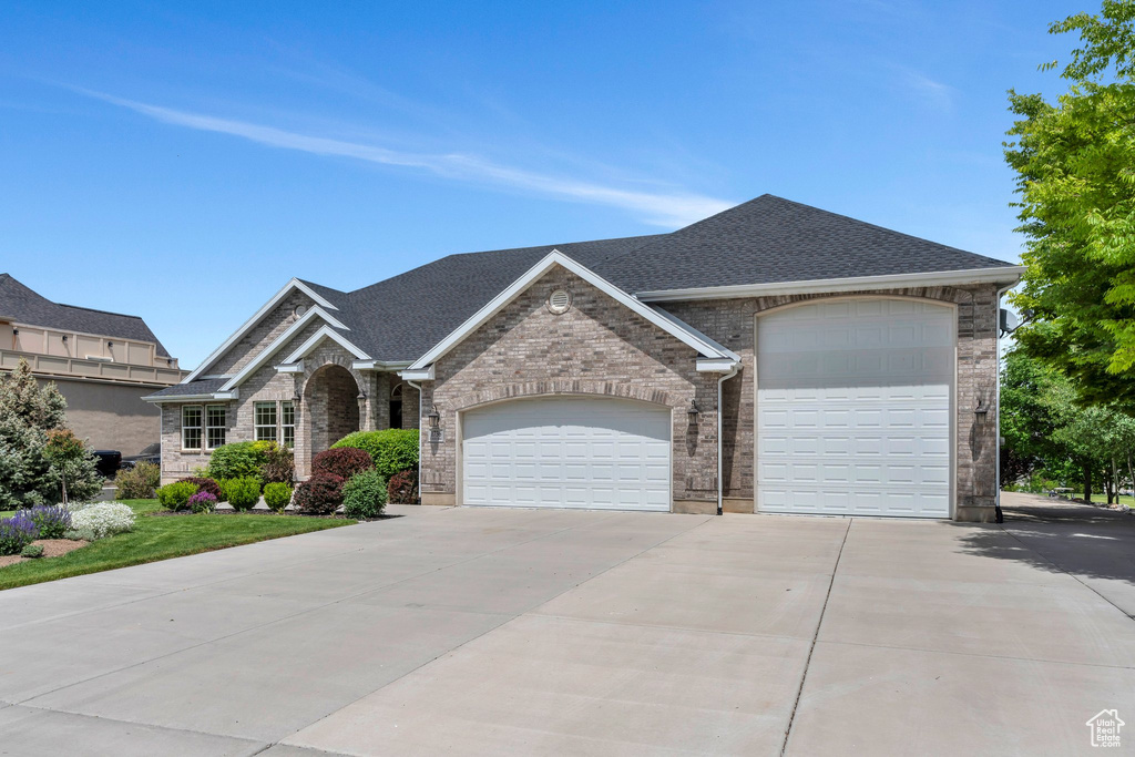 View of front of home featuring concrete driveway, a garage, a shingled roof, and brick siding