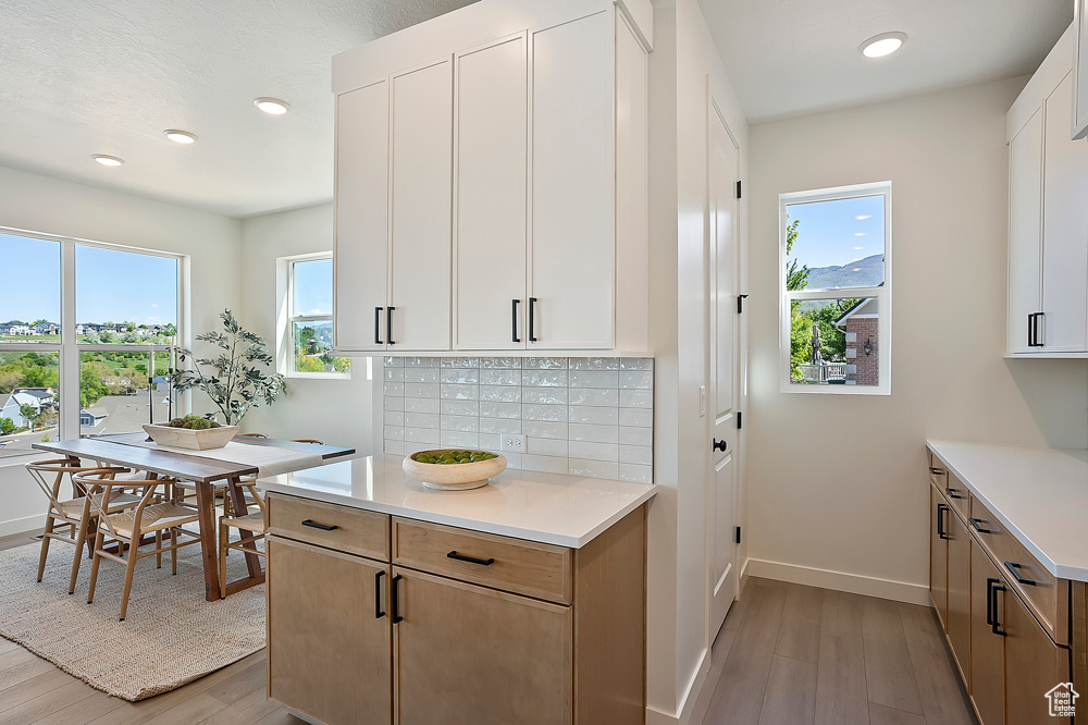 Kitchen with light countertops, light wood-type flooring, tasteful backsplash, baseboards, and recessed lighting