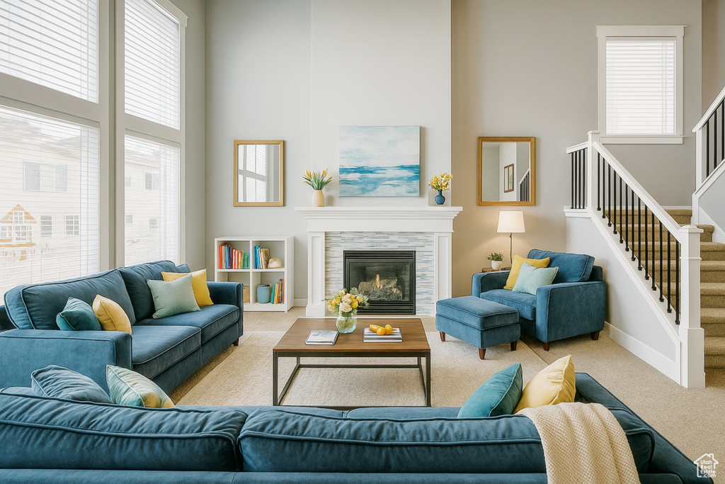 Carpeted living room with a towering ceiling, healthy amount of natural light, stairway, baseboards, and a tiled fireplace