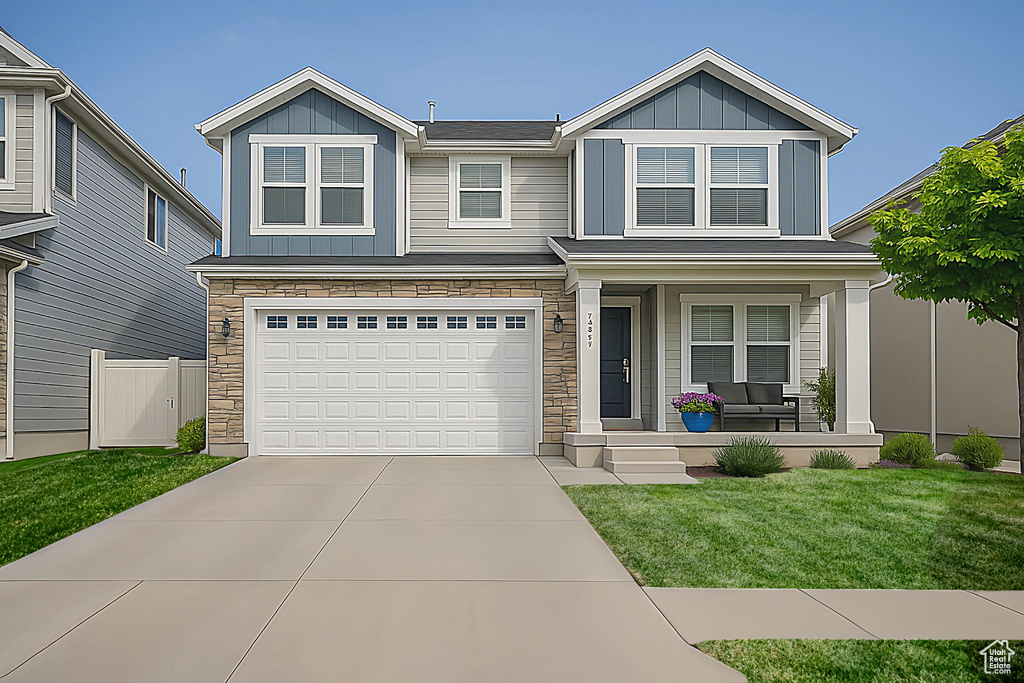 View of front facade with covered porch, board and batten siding, stone siding, and concrete driveway