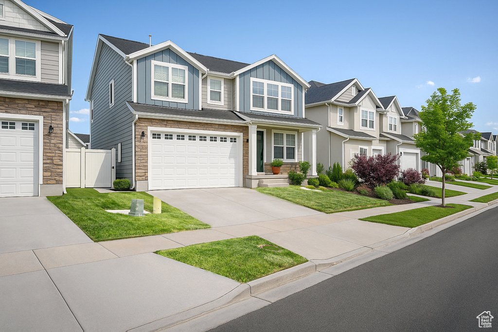 View of front of house with stone siding, board and batten siding, a residential view, driveway, and an attached garage