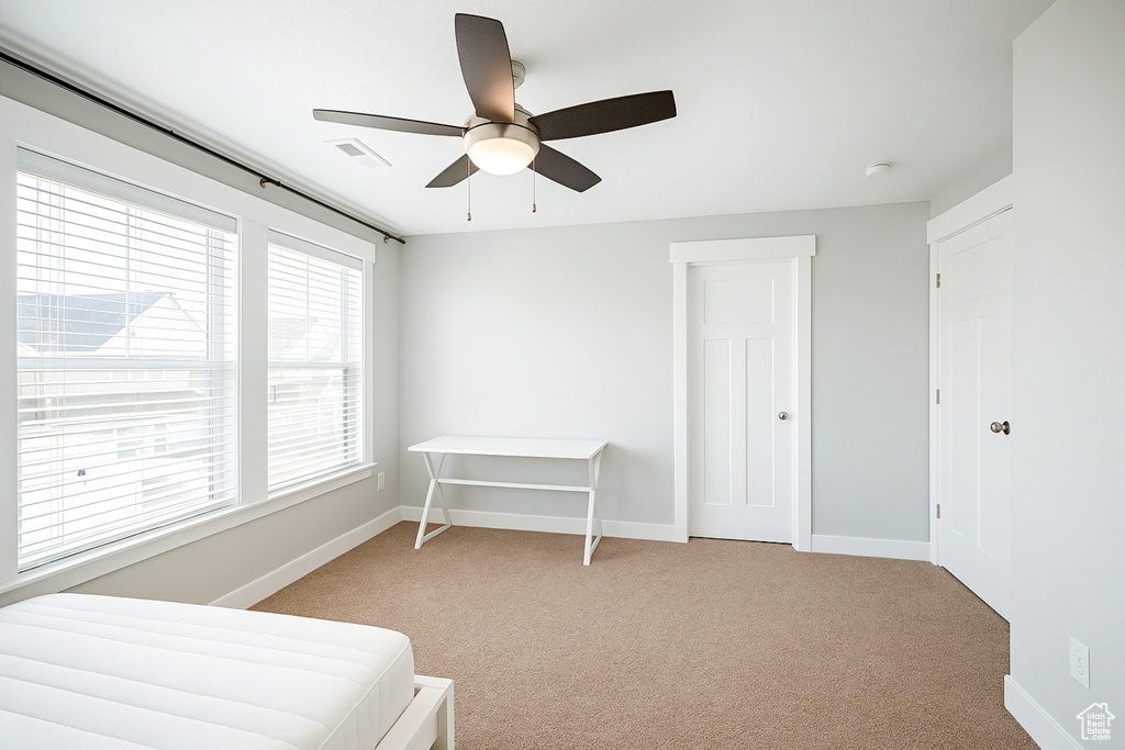 Bedroom with light carpet, baseboards, and a ceiling fan