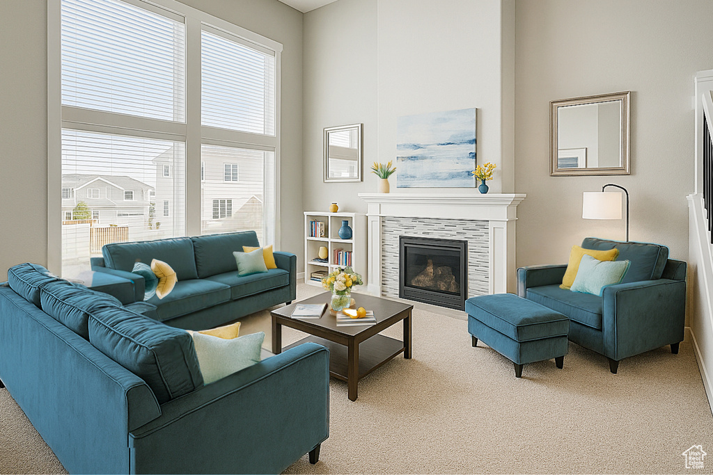 Living room featuring light carpet, healthy amount of natural light, a tiled fireplace, and a high ceiling