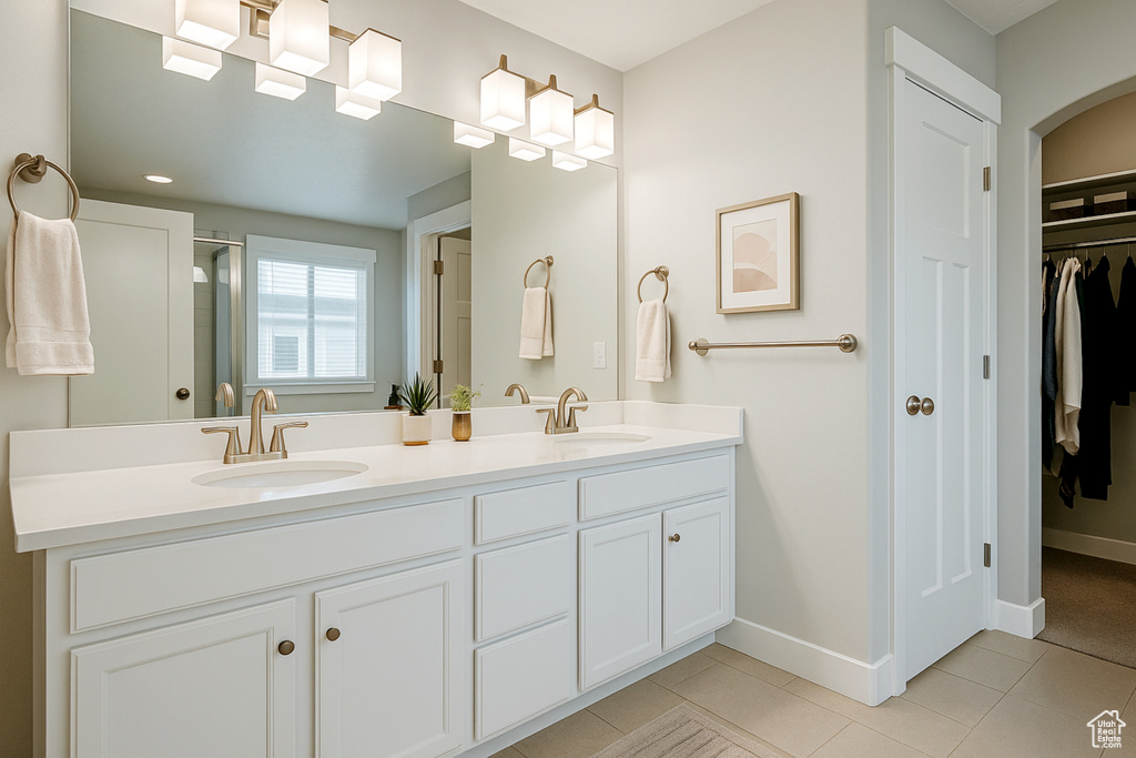 Bathroom featuring double vanity, a spacious closet, baseboards, tile patterned floors, and a shower with shower door