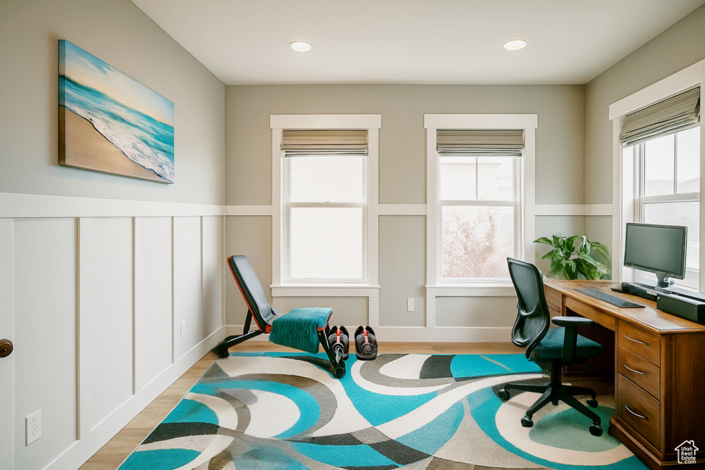 Office area with light wood-style flooring, recessed lighting, and a wainscoted wall