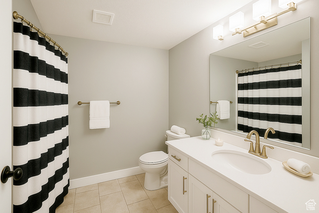 Full bathroom featuring tile patterned floors, toilet, vanity, baseboards, and curtained shower