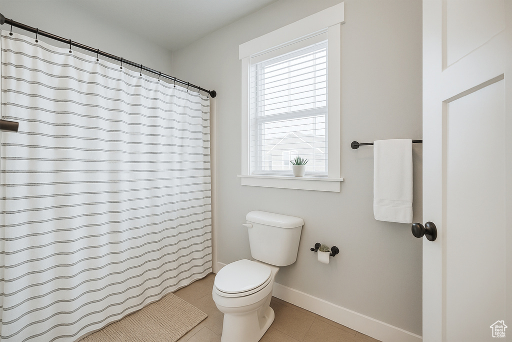 Full bathroom with toilet, baseboards, tile patterned flooring, and a shower with shower curtain