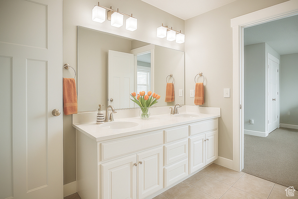 Bathroom featuring double vanity, tile patterned floors, and baseboards