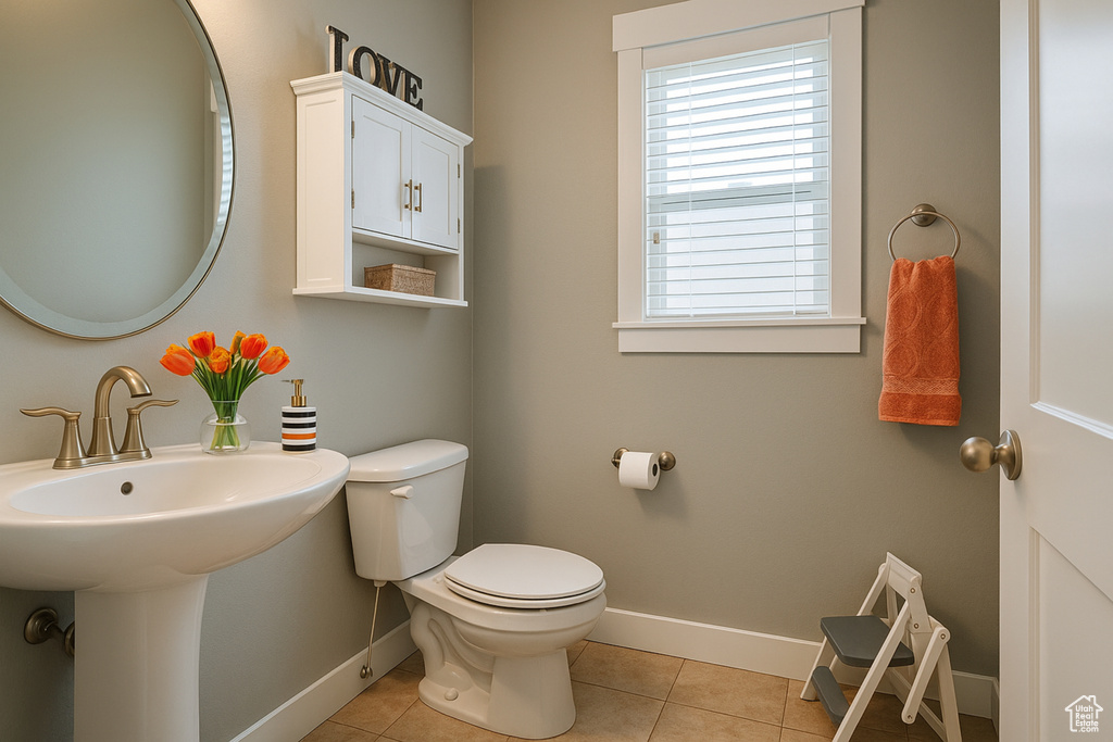 Half bathroom with baseboards, toilet, and tile patterned flooring