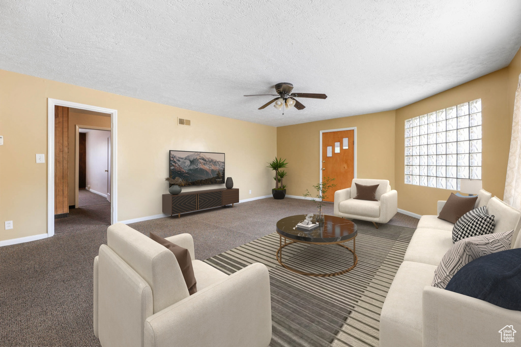 Carpeted living room with a ceiling fan, a textured ceiling, and baseboards