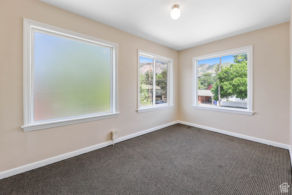 Unfurnished room with dark colored carpet and baseboards