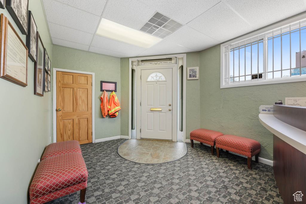 Entrance foyer with baseboards, a paneled ceiling, a textured wall, and tile patterned floors