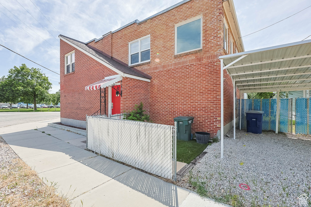 View of side of property featuring brick siding, driveway, and a carport