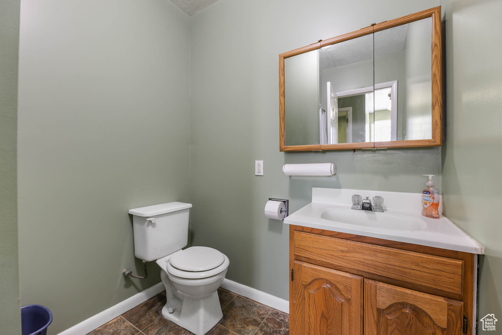 Bathroom with toilet, baseboards, and vanity