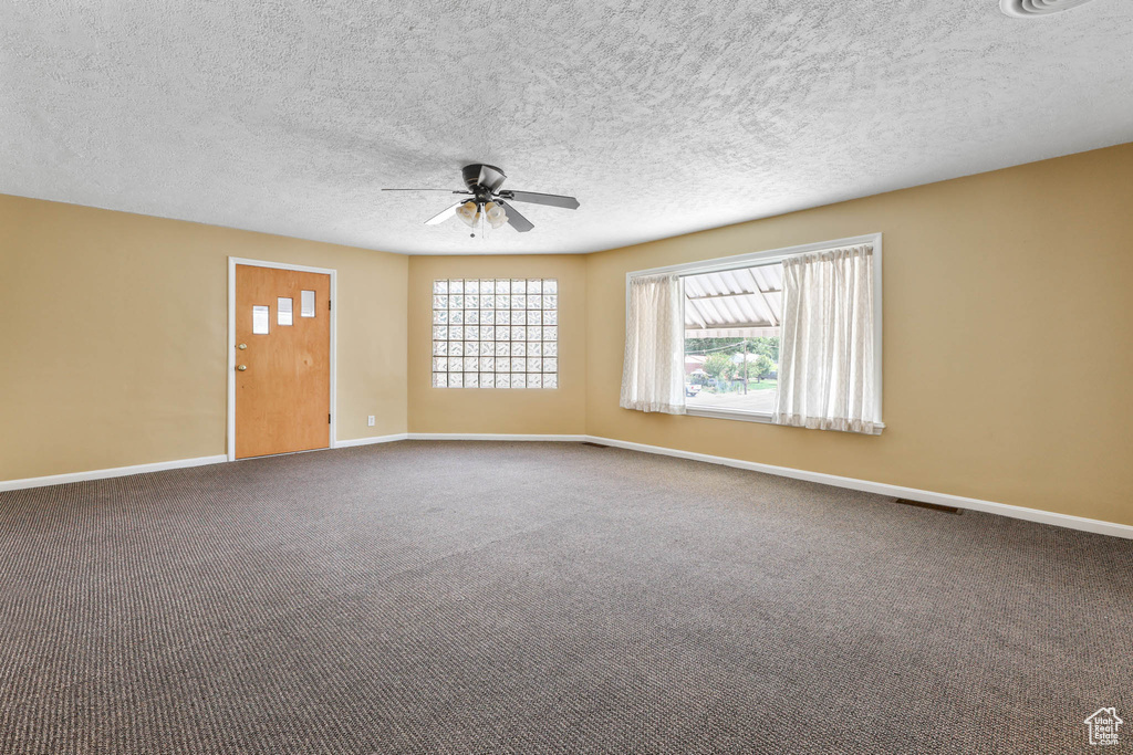 Spare room featuring a ceiling fan, baseboards, carpet, and a textured ceiling