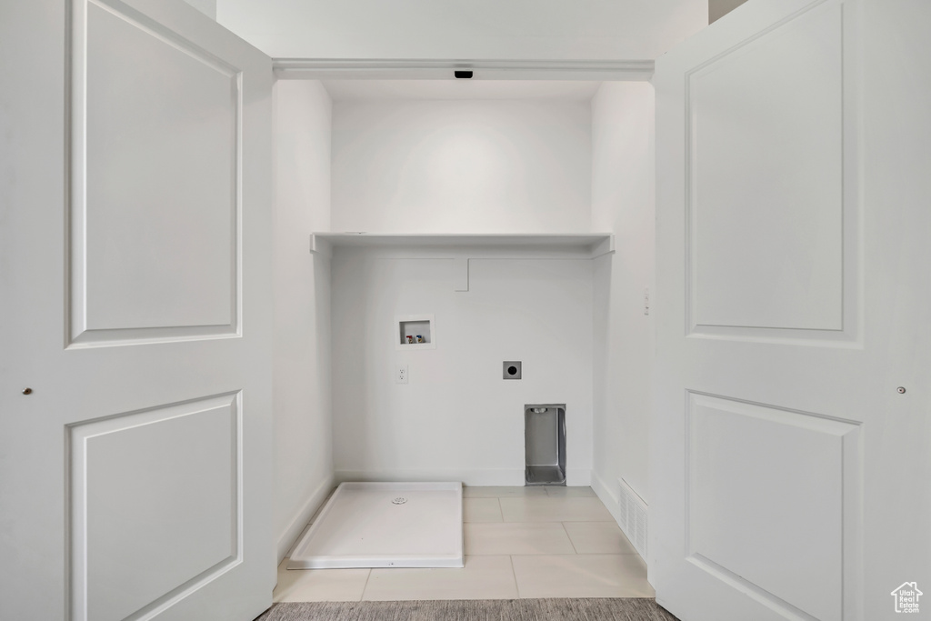 Washroom featuring hookup for a washing machine, electric dryer hookup, light tile patterned floors, and baseboards