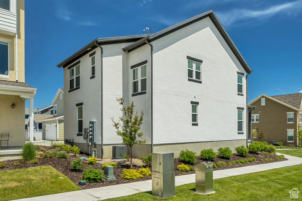 View of home\\\\\\\'s exterior with stucco siding, a yard, and central AC