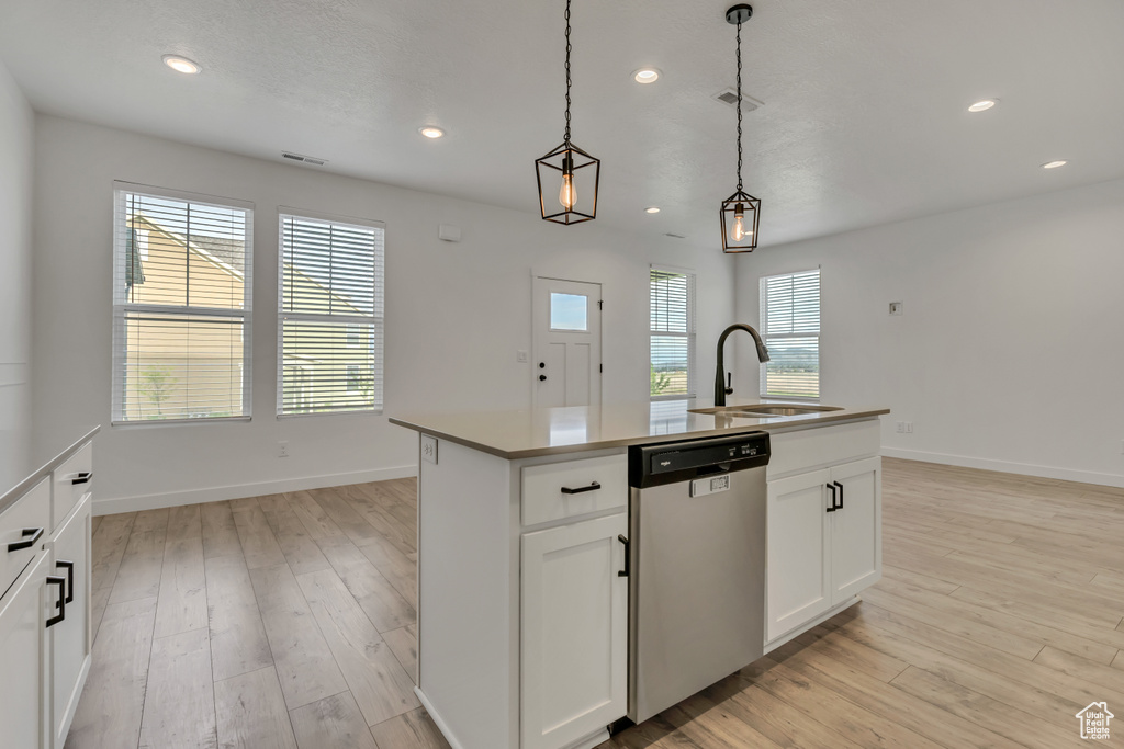 Kitchen featuring stainless steel dishwasher, a sink, light wood-style floors, pendant lighting, and recessed lighting