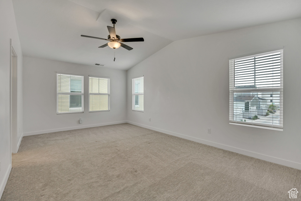 Spare room with lofted ceiling, ceiling fan, light colored carpet, and baseboards