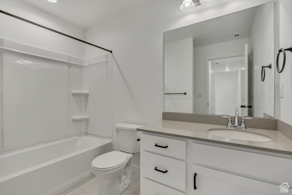 Full bath with toilet, vanity, tile patterned floors, and shower / washtub combination