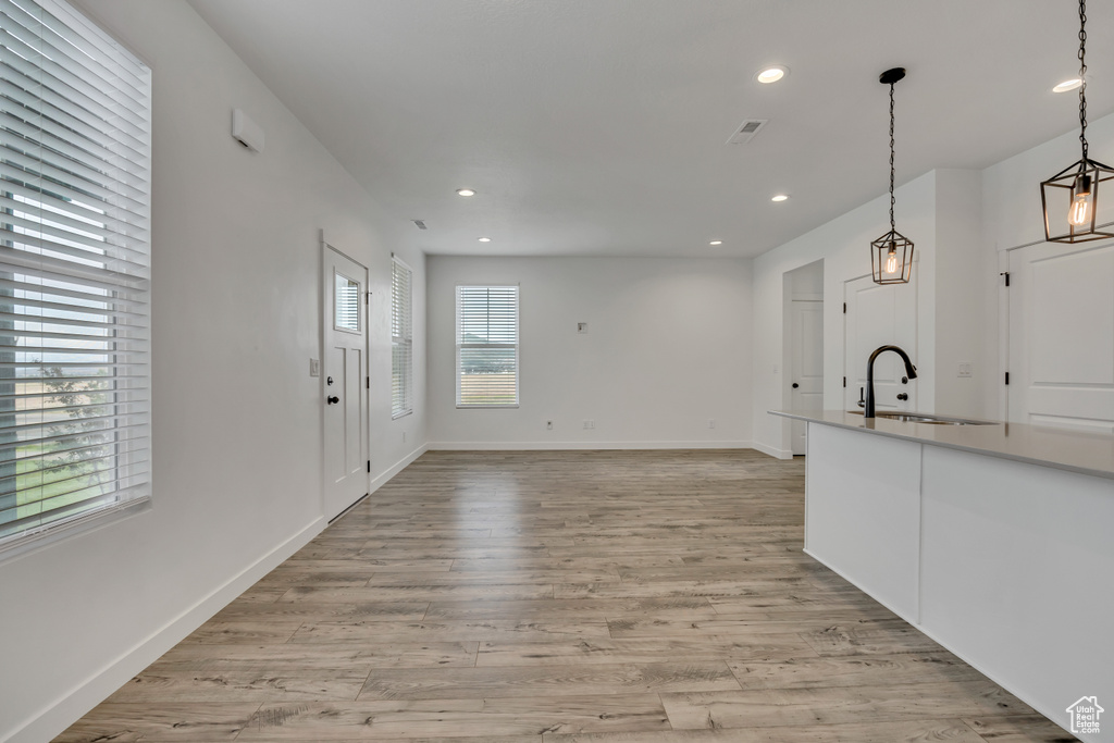 Kitchen featuring a sink, recessed lighting, hanging light fixtures, light wood-style floors, and baseboards