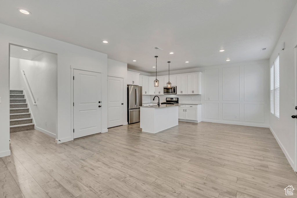 Unfurnished living room with stairway, light wood-style floors, recessed lighting, a sink, and baseboards