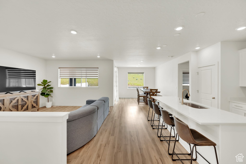 Living room with recessed lighting, plenty of natural light, light wood-type flooring, and baseboards