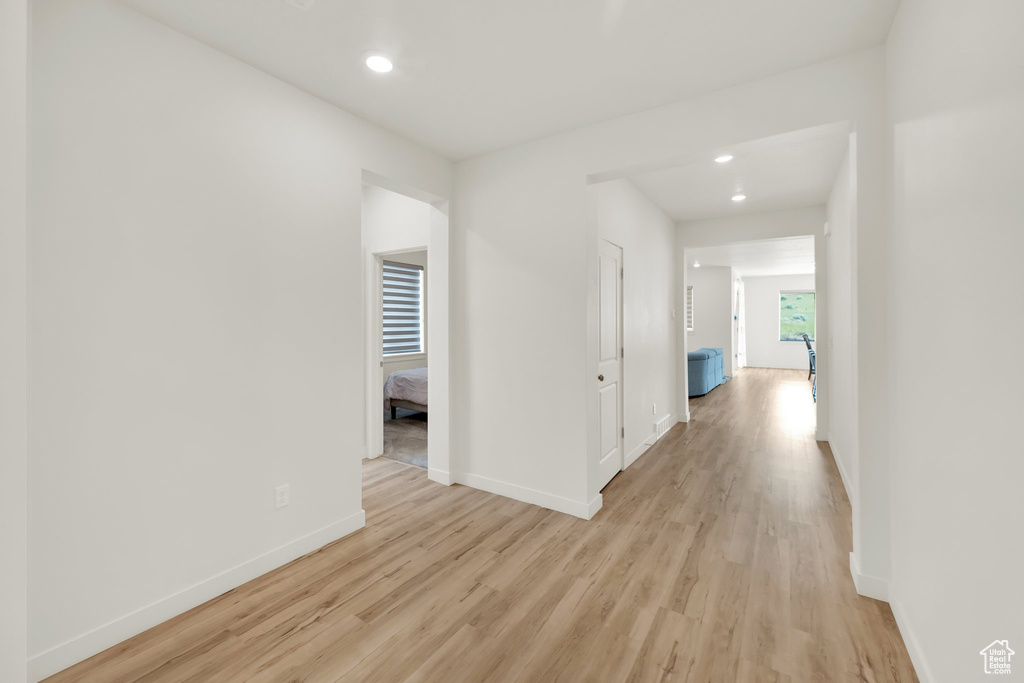Hallway featuring light wood-style flooring, baseboards, and recessed lighting