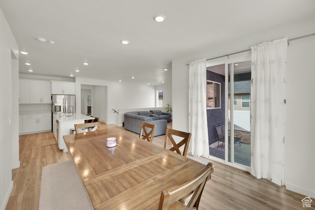 Dining room with light wood finished floors and recessed lighting