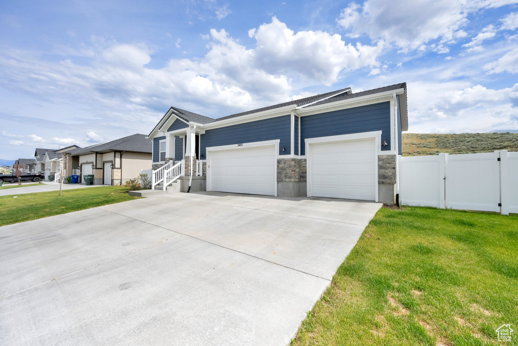 Ranch-style home featuring concrete driveway, a gate, a garage, and stone siding