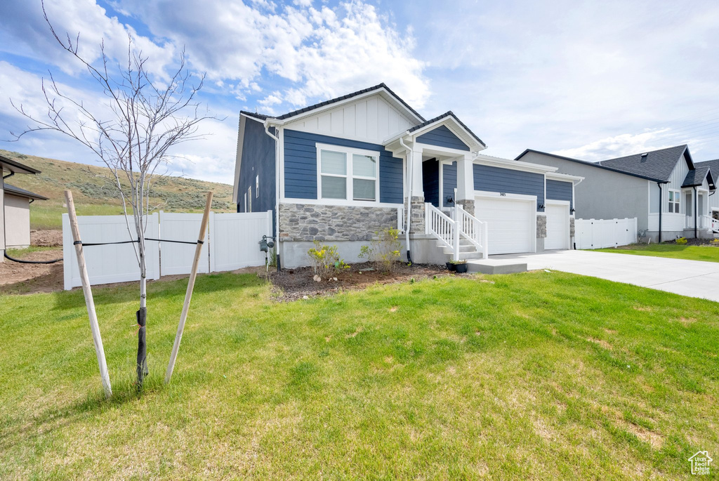 View of front of home featuring a garage, concrete driveway, board and batten siding, and stone siding