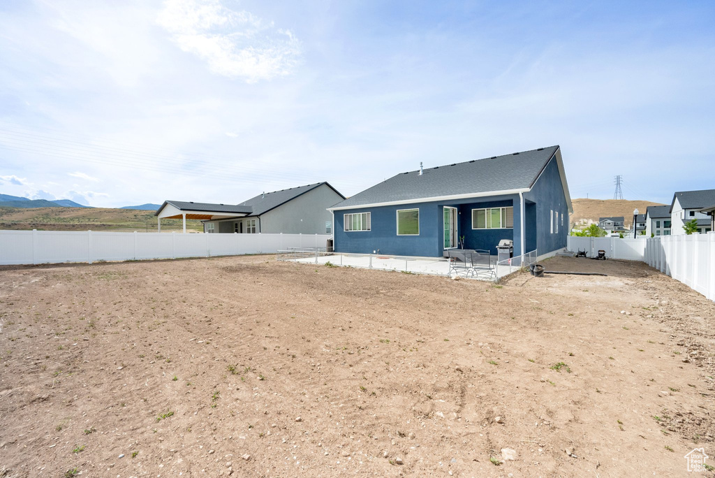 Rear view of property featuring a fenced backyard, a patio, and roof with shingles