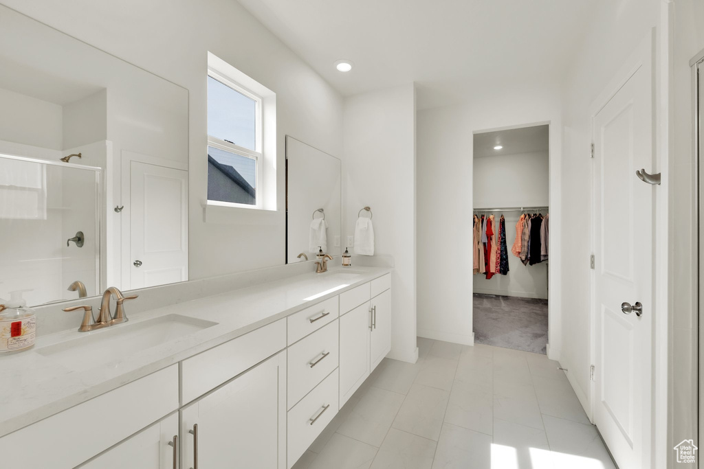 Bathroom featuring double vanity, a stall shower, a walk in closet, recessed lighting, and tile patterned floors