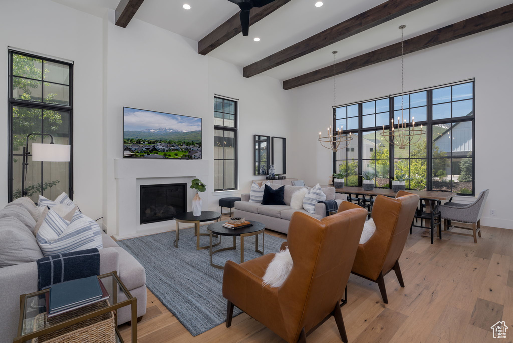 Living room featuring a chandelier, beamed ceiling, light wood-style floors, recessed lighting, and plenty of natural light