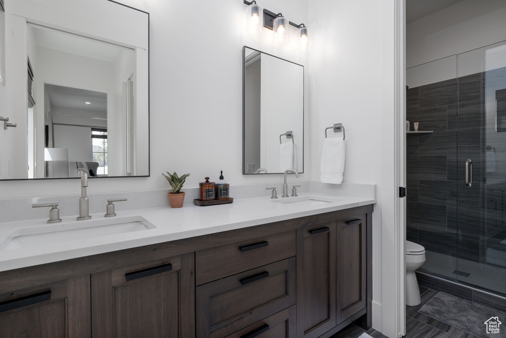 Full bathroom with double vanity, toilet, and a stall shower