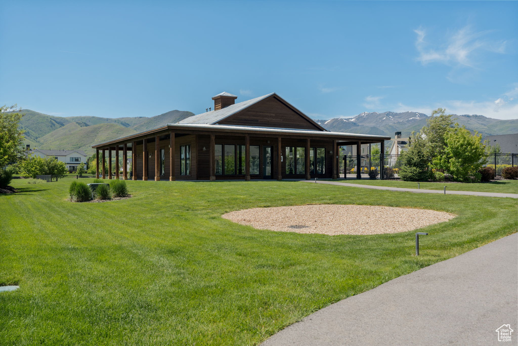 Back of property with a mountain view and a yard