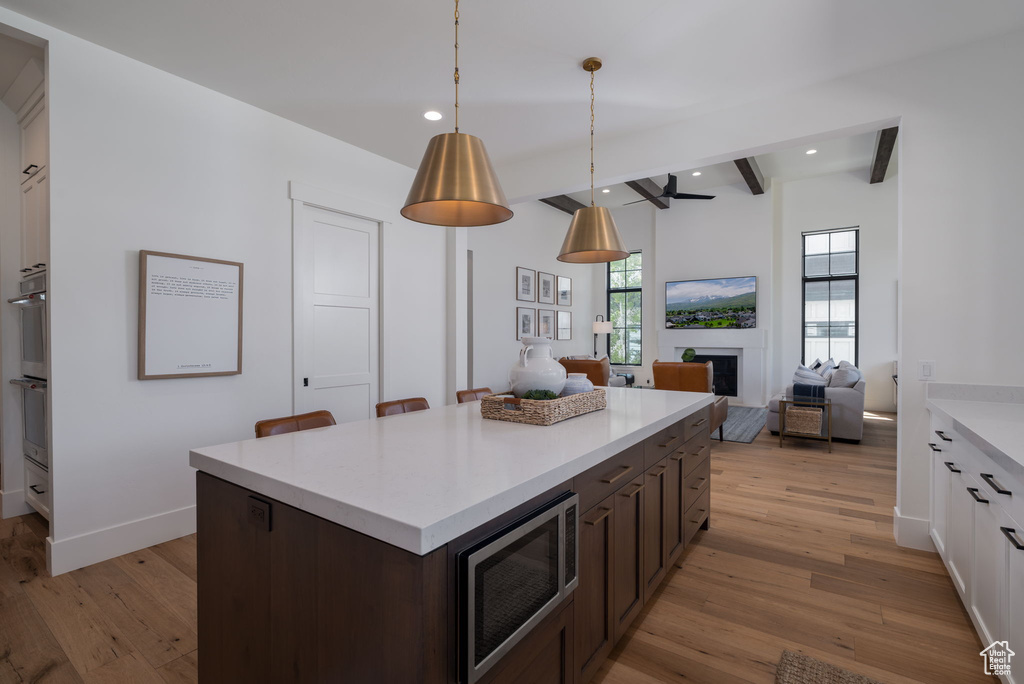 Kitchen featuring stainless steel microwave, light wood-style floors, light countertops, recessed lighting, and dark brown cabinets