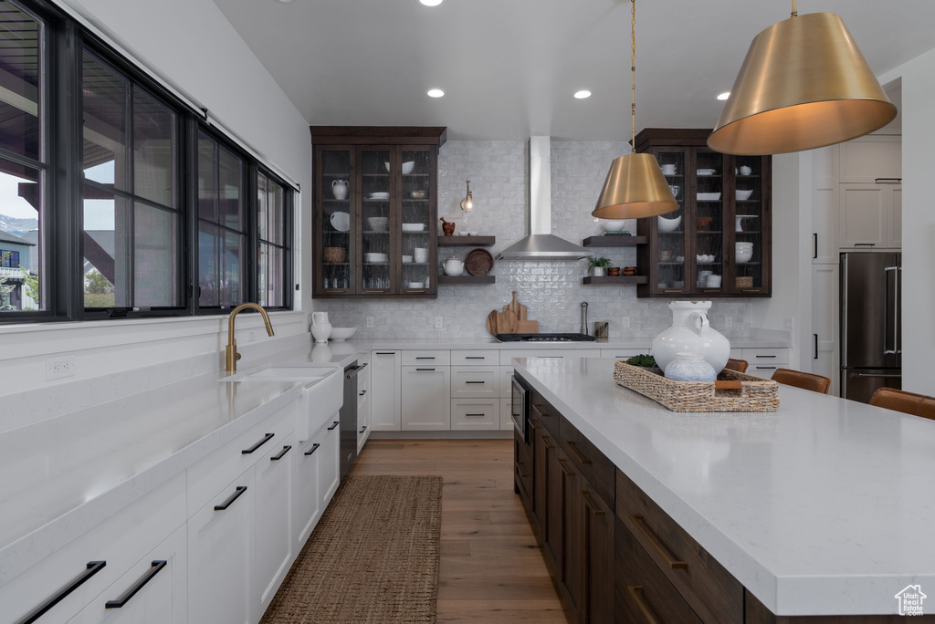 Kitchen with appliances with stainless steel finishes, dark brown cabinets, open shelves, wood finished floors, and backsplash